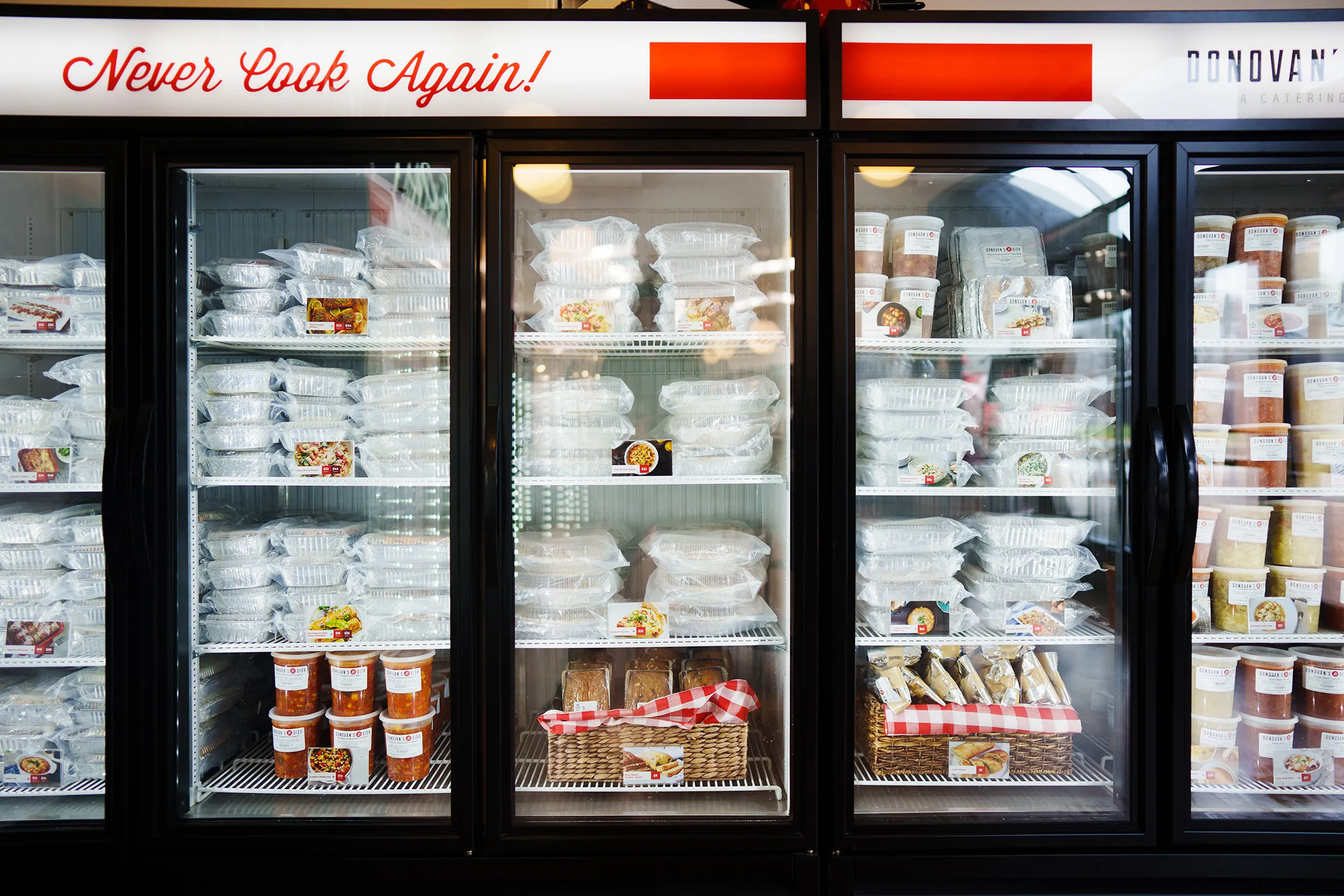 Donovan's Dish retail freezers stocked with packaged meals under a Never Cook Again! sign