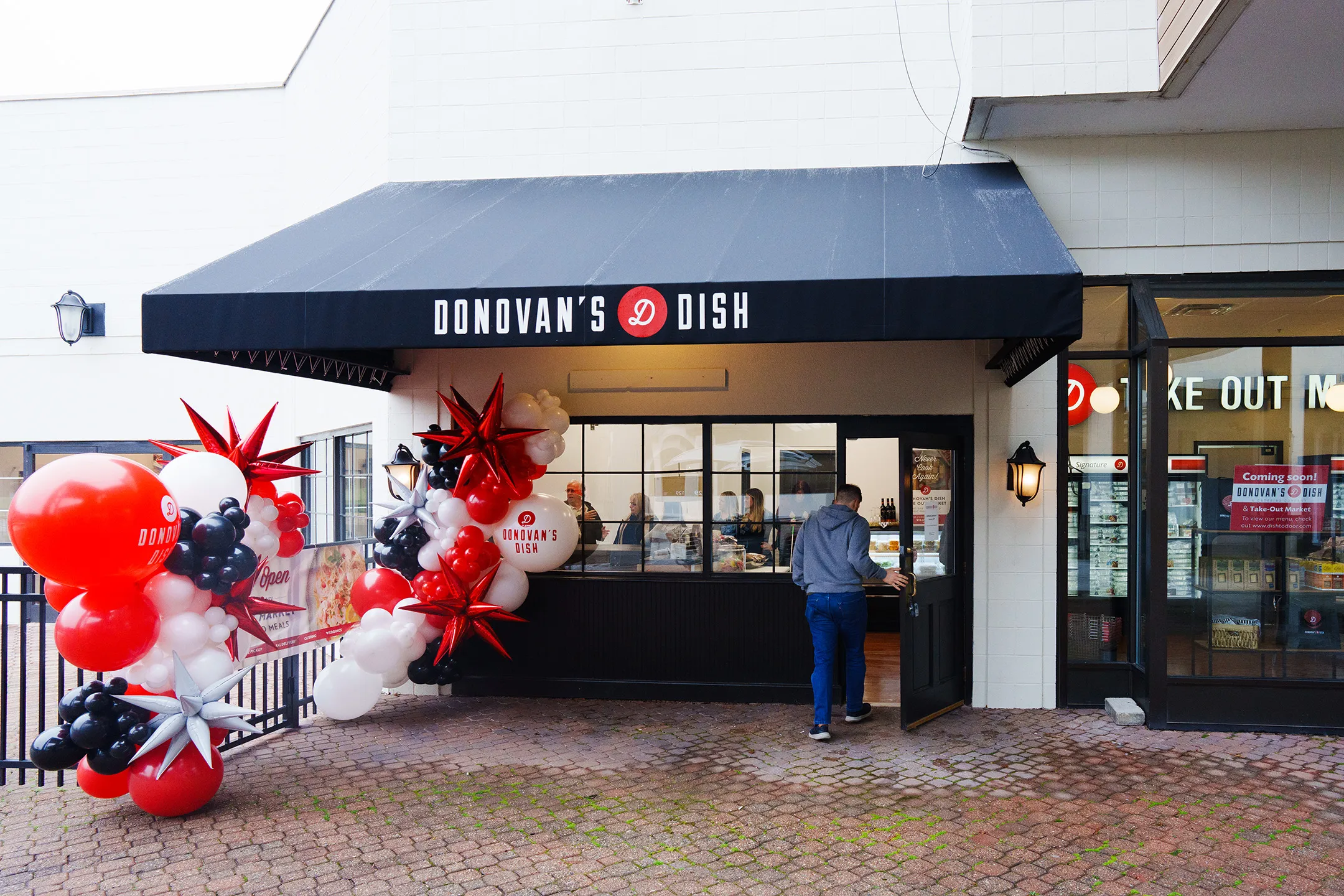 The Donovan's Dish Take-Out Market storefront on opening day, framed by red, white and black balloons
