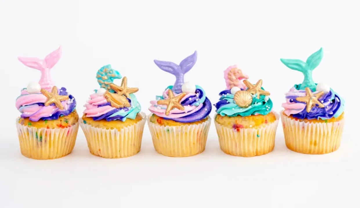Five Sweet E's mermaid cupcakes topped with pastel swirls, gold starfish and fondant tails